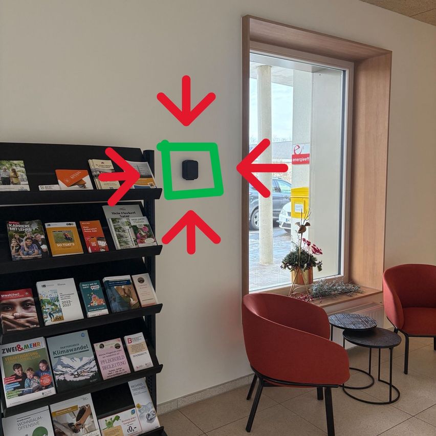 Ein Raum mit einem Bücherregal voller Bücher, roten Stühlen und einem Glasfenster mit Pfeilen, die nach links und rechts zeigen.