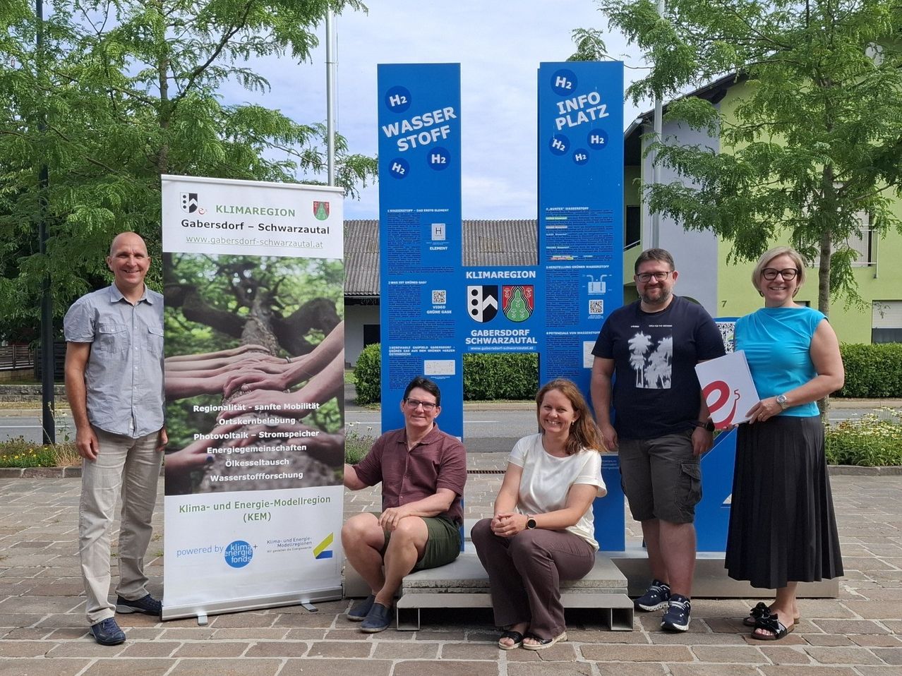 A group of people stand in front of informational signs about the climate region and a model region for climate and energy.