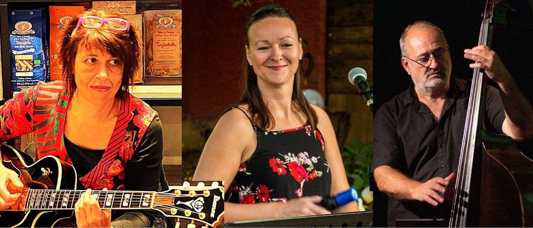 Eine Frau in einem Blumenkleid lächelt, während sie ein Mikrofon hält und eine Gitarre im Vordergrund steht.