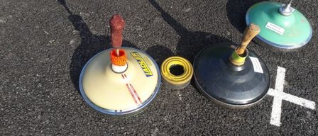 Drei Verkehrskegel stehen auf einer Straße mit einem gelben und einem grünen Kegel vor einem weißen Buchstaben X.