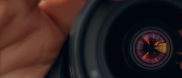 Eine Person hält eine Kameralinse nah an, um die komplexen Details der Linse zu zeigen.