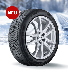 Ein neuer Winterreifen mit einem silbernen Leichtmetallrad auf einer verschneiten Straße. Der Reifen ist mit 'RATIN' gekennzeichnet und hat einen roten 'NEU'-Aufkleber.