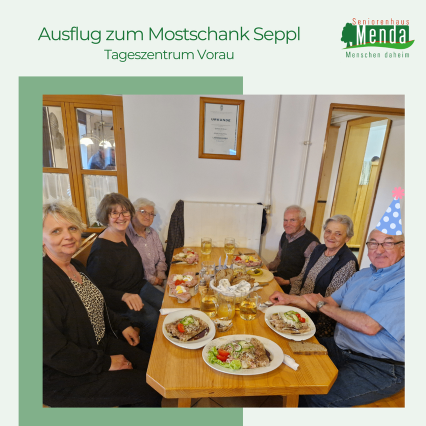 Eine Gruppe älterer Menschen feiert einen Geburtstag an einem Tisch, umgeben von Essen und Getränken.