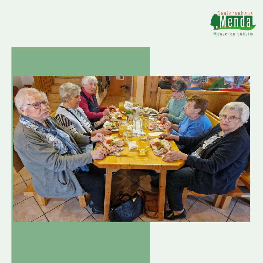 Mehrere ältere Frauen sitzen in einem Restaurant an einem Tisch und genießen eine Mahlzeit. Jede Person hat einen Teller mit Essen vor sich, und es gibt Gläser Orangensaft. Das Restaurant hat Holzwände und -böden.