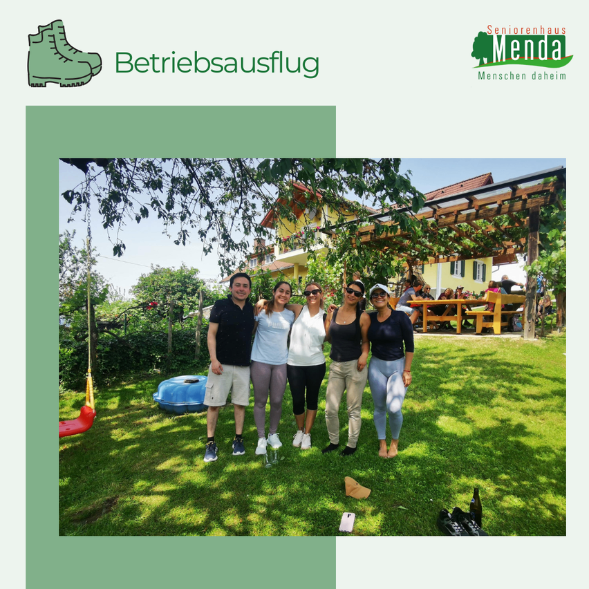 Fünf Menschen stehen in einem Garten und lächeln für ein Foto. Dahinter steht ein Haus mit einem Holzzaun.