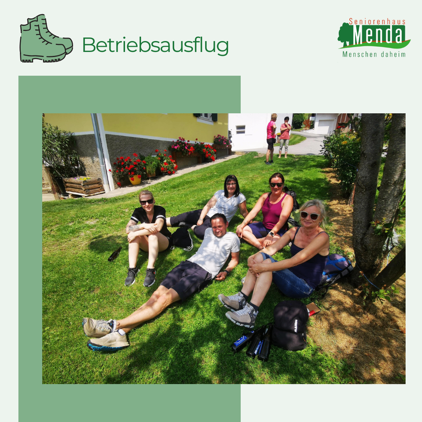 Eine Gruppe von Menschen sitzt auf dem Gras. Sie genießen ihren Tag. Vor ihnen steht ein Baum.