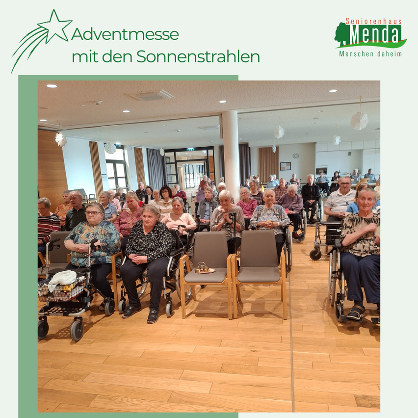 Eine Adventsmesse im Seniorenhaus Menda mit Sonnenstrahlen. Viele ältere Menschen sitzen in Rollstühlen, einige klatschen. Der Raum hat einen Holzboden und Glasfenster.