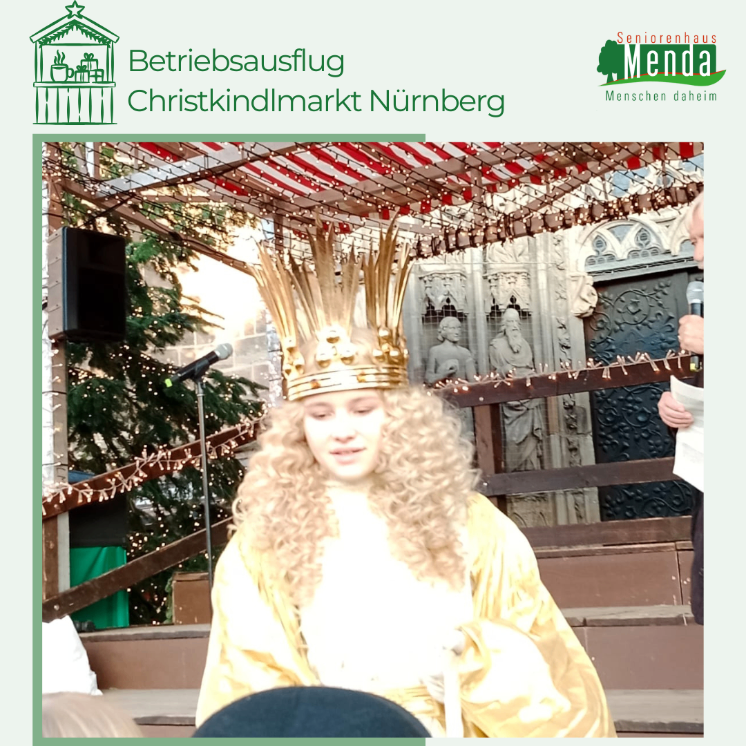 Eine junge Frau mit goldener Krone und gelbem Gewand steht in einer festlichen Umgebung mit einem Weihnachtsbaum und Lautsprechern. Hinter ihr sind eine Statue und eine Person mit Mikrofon zu sehen.