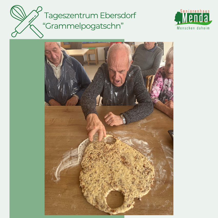Ein älterer Mann macht Teig an einem Holztisch. Andere ältere Menschen sitzen hinter ihm. Ein Schild in der oberen linken Ecke zeigt 'Tageszentrum Ebersdorf'. Der Name 'Grammelpogatschn' wird ebenfalls angezeigt.