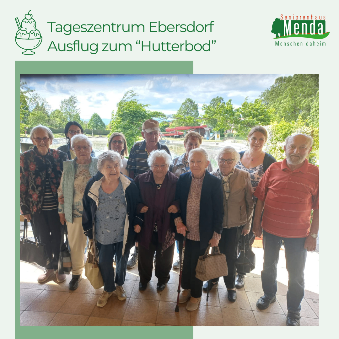 Eine Gruppe älterer Menschen posiert für ein Foto am Ort 'Hutterbod', mit einem Logo von Seniorenhaus Menda.