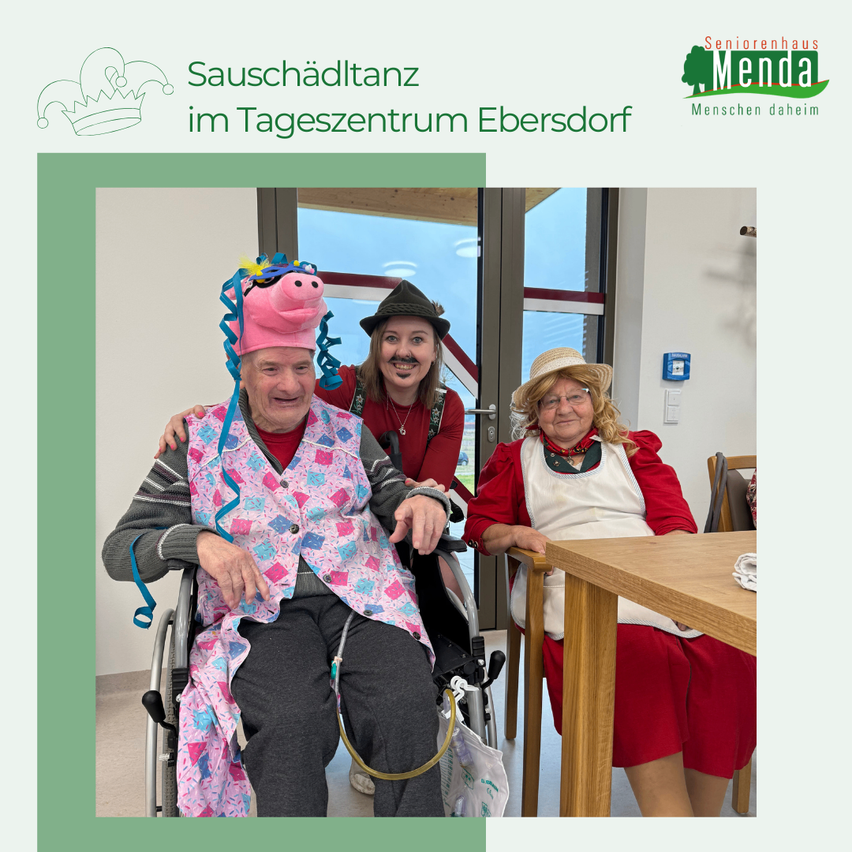 Ein älterer Mann im Rollstuhl trägt einen Schweinehut und eine rosa Weste. Eine Frau in einem roten Kleid sitzt neben ihm. Eine weitere Frau in einem roten Kleid und Hut sitzt an einem Tisch. Der Hintergrund ist eine Tür mit einem Logo.