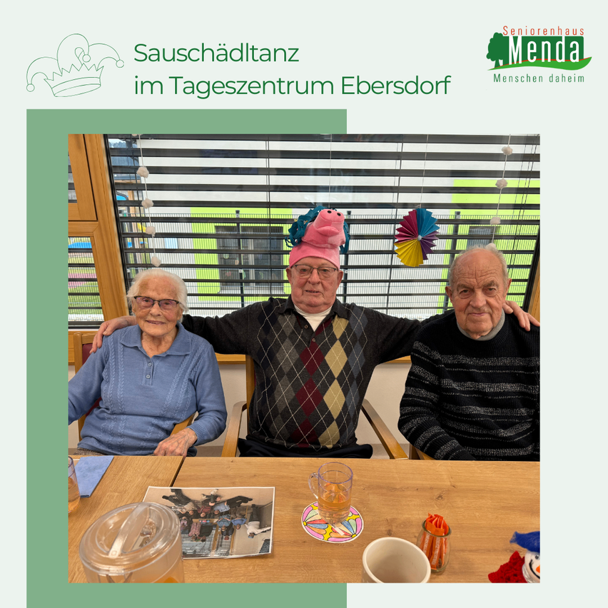 Drei ältere Menschen sitzen zusammen an einem Tisch, lächeln und tragen Hüte. Hinter ihnen befindet sich ein Fenster mit Jalousien. Im Hintergrund ist ein bunter Banner mit Text und Logo.