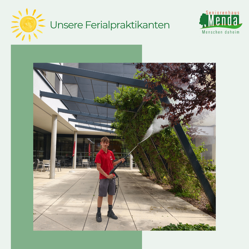 Ein junger Mann reinigt eine grüne Wand mit einem Wassersprüher an einem sonnigen Tag.