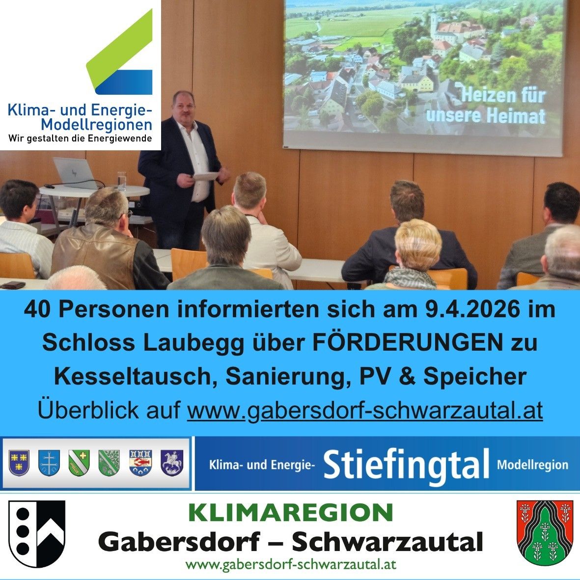 A man speaks in a conference hall with a screen displaying a village scene. The text reads about a meeting on April 9, 2026, about funding for kettle exchange, sanitation, PV, and storage.