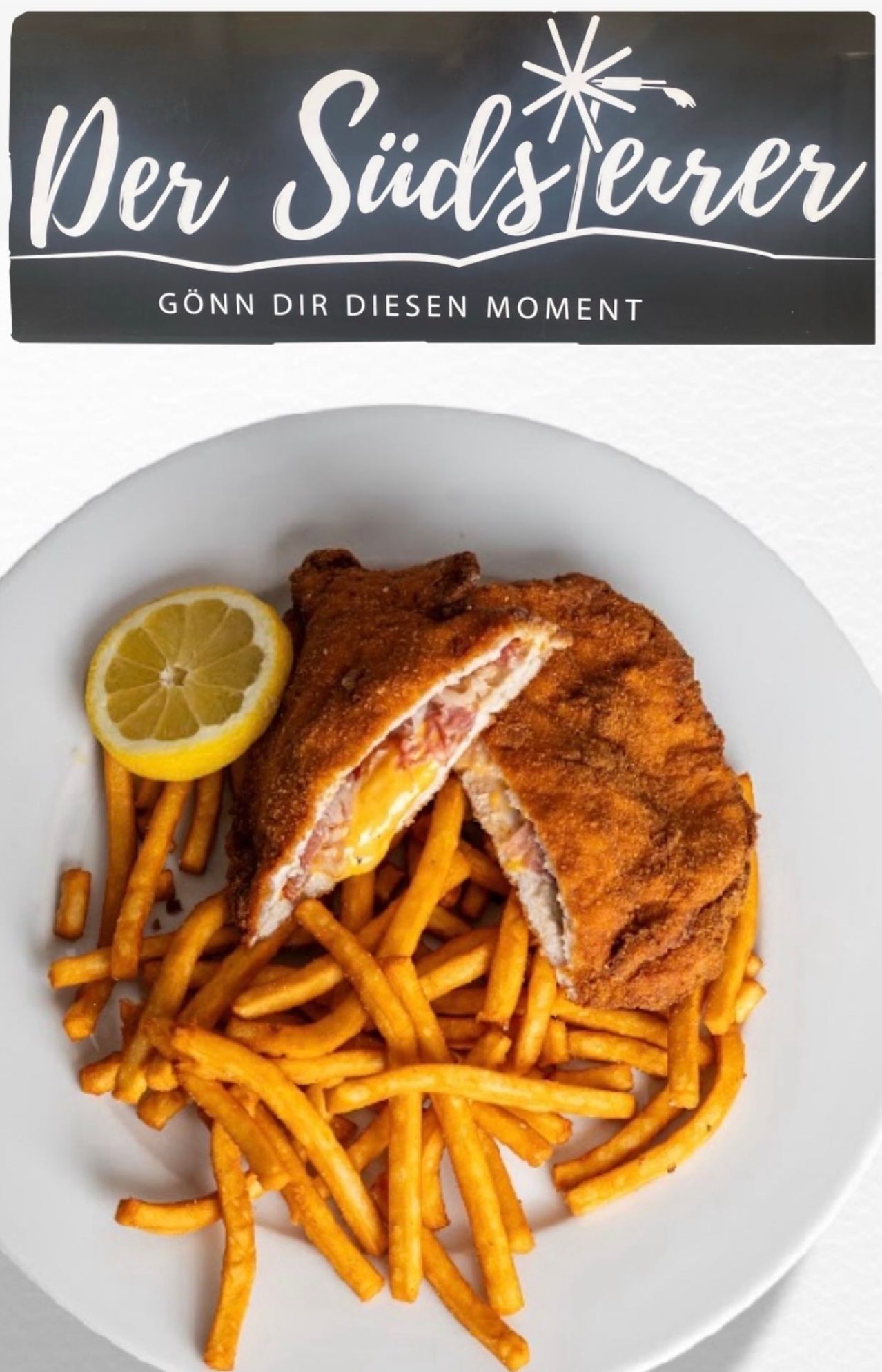 A white plate with a crispy fried chicken cutlet, melted cheese, and a slice of lemon, accompanied by golden french fries.