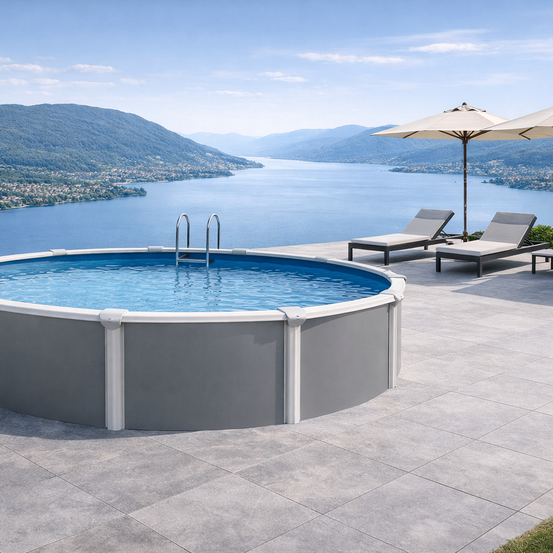 Ein ovaler Pool mit grauem Rahmen und blauem Innenraum steht auf einer Terrasse mit Seeblick. Zwei Liegestühle und Sonnenschirme sind in der Nähe aufgestellt.
