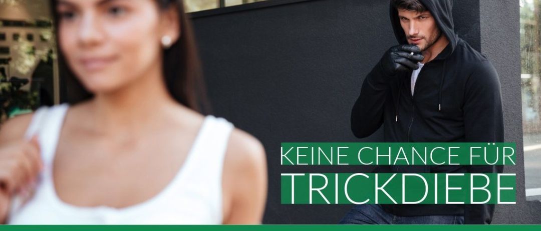 Eine Frau in einem weißen Tanktop und ein Mann in einer schwarzen Kapuzenpulli stehen vor einer schwarzen Wand mit grünem Text.