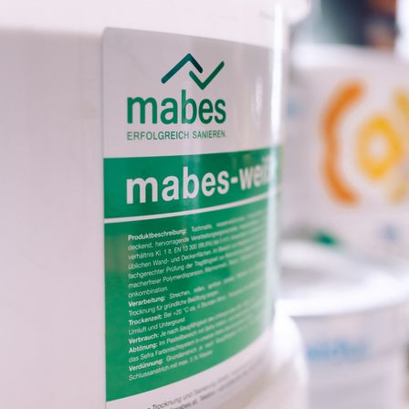 Nahaufnahme einer weißen Flasche mit dem Label 'mabes'. Grüner Text liest 'mabes-wei'. Enthält Produktbeschreibung, Anweisungen und Warnhinweise.