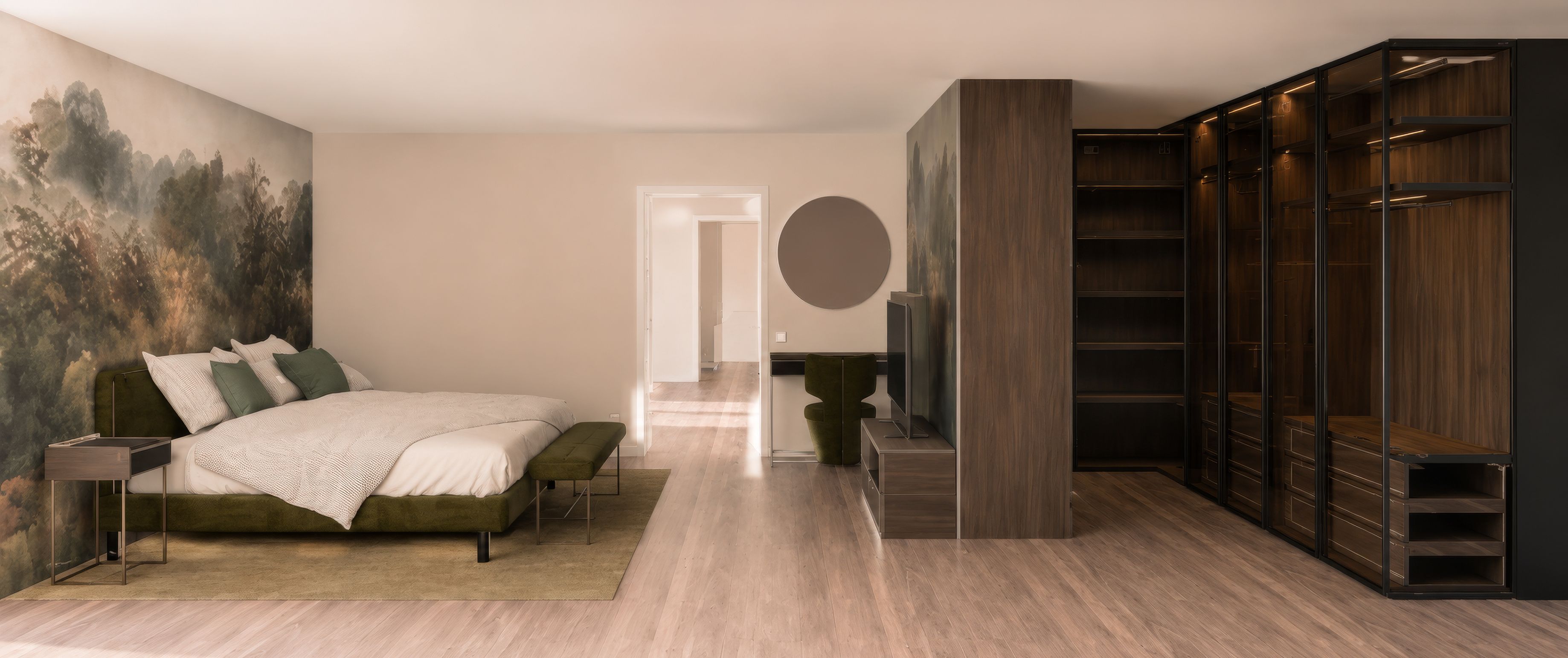 Ein Schlafzimmer mit einem Bett, einem Fernseher, einem grünen Sessel und einer runden Wanddekoration. Der Boden ist hölzern und die Wände weiß. Es gibt eine Tür zu einem anderen Raum.