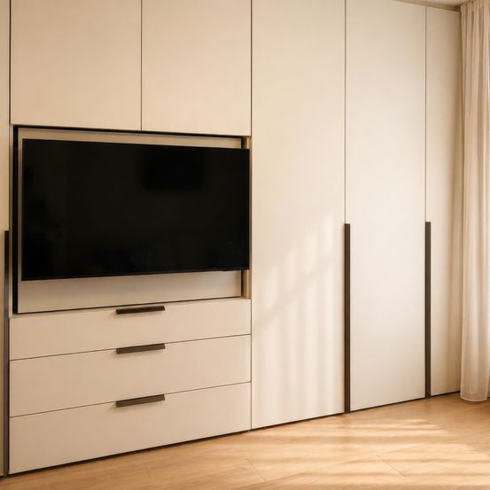 Ein modernes Wohnzimmer mit einem weißen Schrank, der einen über Schubladen montierten Fernseher aufweist, vor einem Holzboden und einem verhangenen Fenster.
