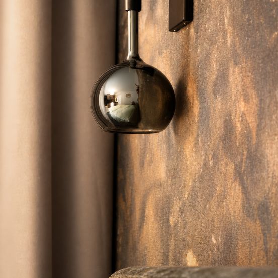 Eine kugelförmige Lampe ist an einer strukturierten Wand montiert und reflektiert Licht und die Umgebung.