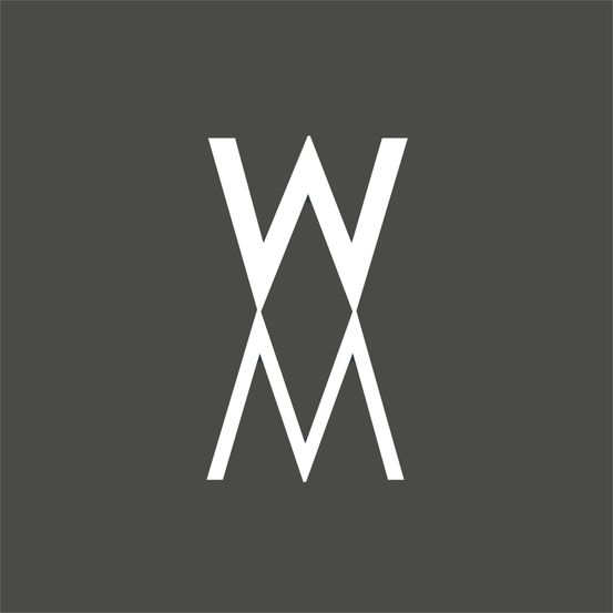 Ein weißes Monogramm mit einem großen W und einem M, die übereinander gestapelt sind, auf einem grauen Hintergrund dargestellt.