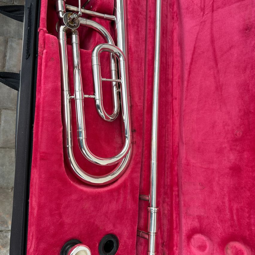 Ein Posaune befindet sich in einem roten Etui mit schwarzem Griff und verfügt über ihren polierten silbernen Korpus und ihren Schiebemechanismus.