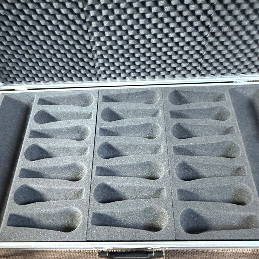 Eine offene Aluminiumbox mit Schaumstoffpolsterung, die für die Aufbewahrung mehrerer konischer Objekte konzipiert ist. Die Box ist grau und der Schaumstoff ist dunkelgrau. Es befinden sich keine Gegenstände in der Box.