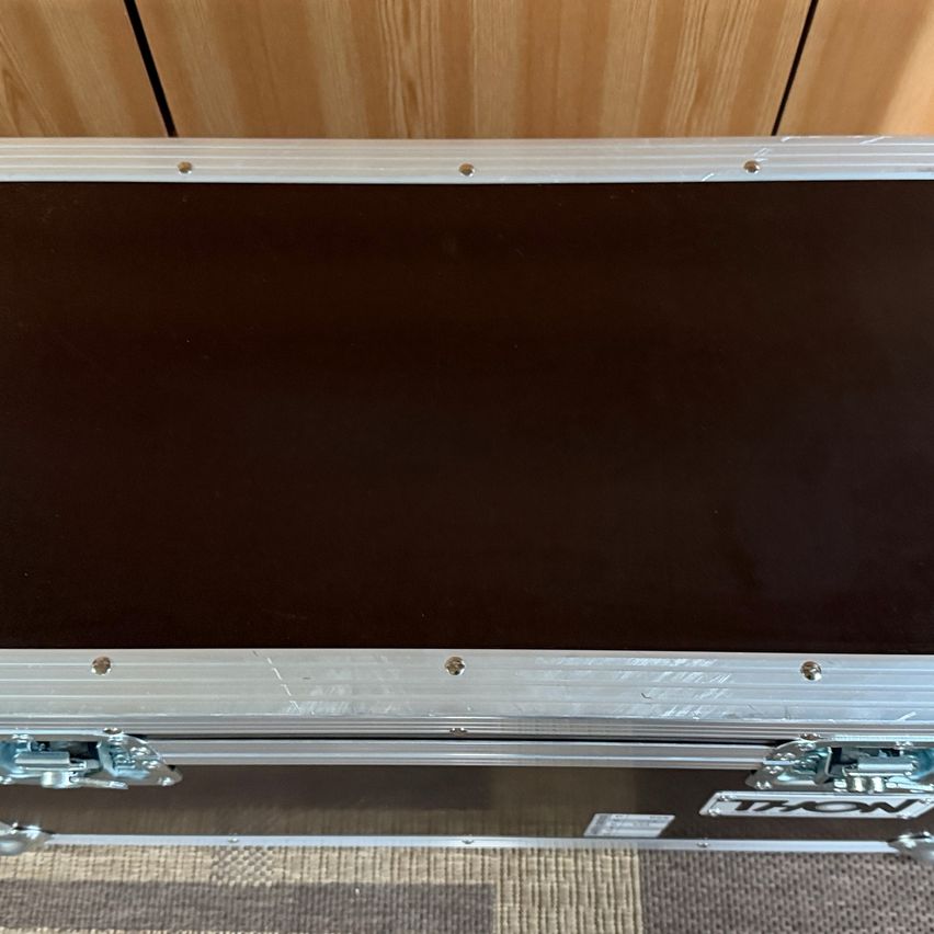 Ein schwarzer und silberumrandeter Koffer ist geöffnet und zeigt ein leeres Inneres mit einer glatten, ebenen Oberfläche. Der Deckel hat Metallgriffe und Schrauben.