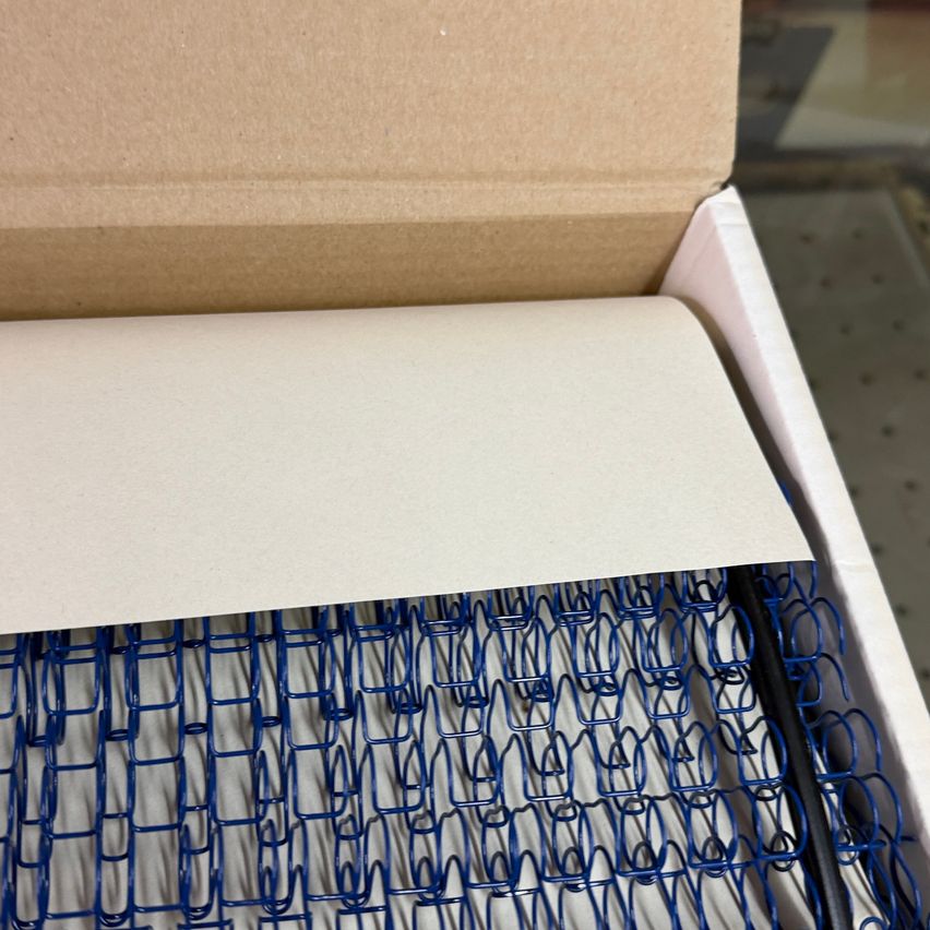 Eine Nahaufnahme einer blauen Federspirale in einem Karton, teilweise geöffnet, um den Inhalt zu zeigen.