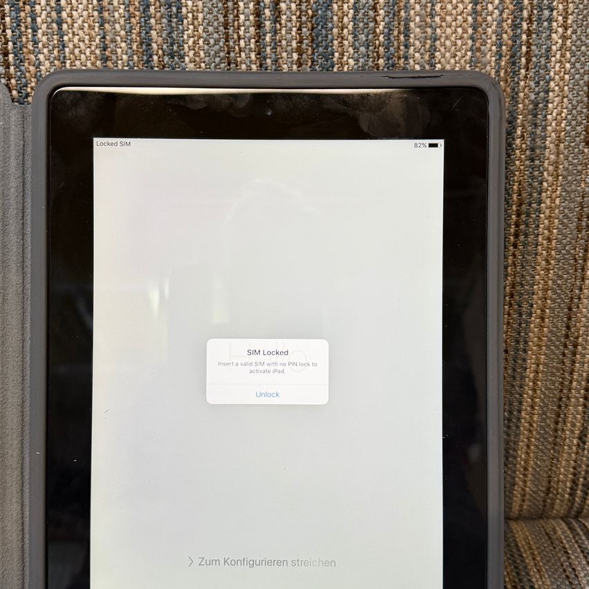 Das iPad ist gesperrt und benötigt eine SIM-Karte ohne PIN-Sperre zum Entsperren. Es befindet sich auf einer gestreiften Oberfläche.