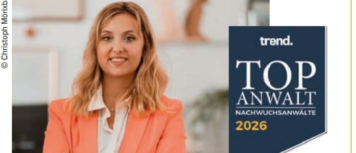 Eine lächelnde Frau im orangefarbenen Blazer steht mit verschränkten Armen da. Das Bild enthält auch ein blaues Schild mit der Aufschrift 'TOP ANWALT 2026'. Die Frau wird für ihre beruflichen Erfolge im juristischen Bereich ausgezeichnet.
