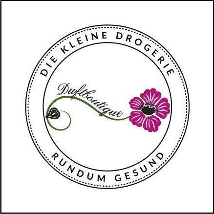 Ein Logo für 'Die Kleine Drogerie Duftboutique' mit einer rosa Blume, einem grünen Blatt und den Worten 'Rundum Gesund' in einem kreisförmigen Design.