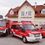 Freiwillige Feuerwehr Ternitz-Döppling-Logo. Drei rote Feuerwehrfahrzeuge sind vor dem Gebäude der F.F. Ternitz-Döpling geparkt, wobei der mittlere Van mit 'FEUERWEHR' und 'KDOF-A' an seiner Seite gekennzeichnet ist.