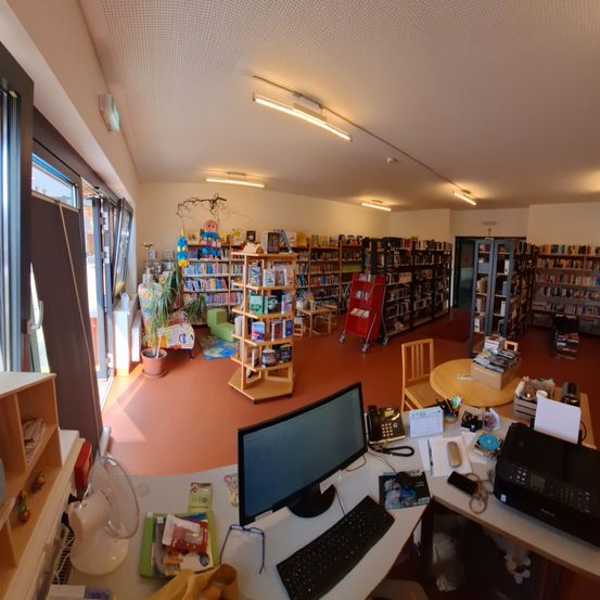 Bild enthält, Furniture, Table, Desk, Screen, Book, Computer Hardware, Monitor, Library, Building, Laptop