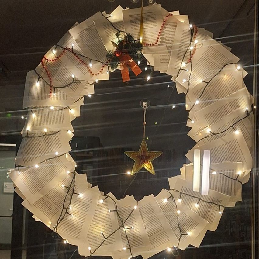 Ein Kranz aus Büchern, dessen Seiten in Blätter verwandelt wurden, ist mit Lichterketten beleuchtet. In der Mitte befindet sich ein Stern.