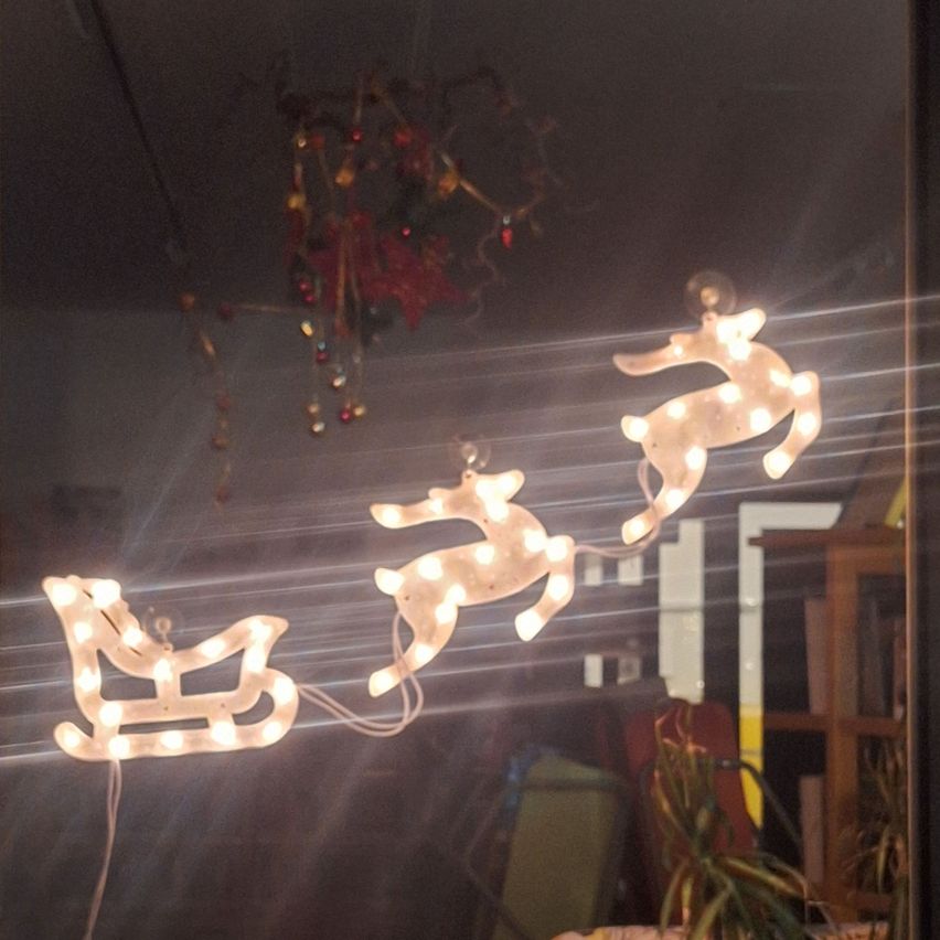 Ein Raum mit Weihnachtsdekorationen, darunter ein Schlitten und leuchtende Rentiere. Die Lichter sind beleuchtet und hängen von der Decke.