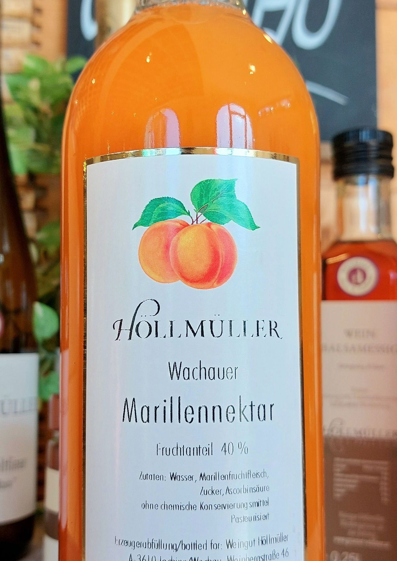 A bottle of Hollmuller Wachauer Marillennektar, a peach nectar with 40% fruit content, is placed between two other bottles.