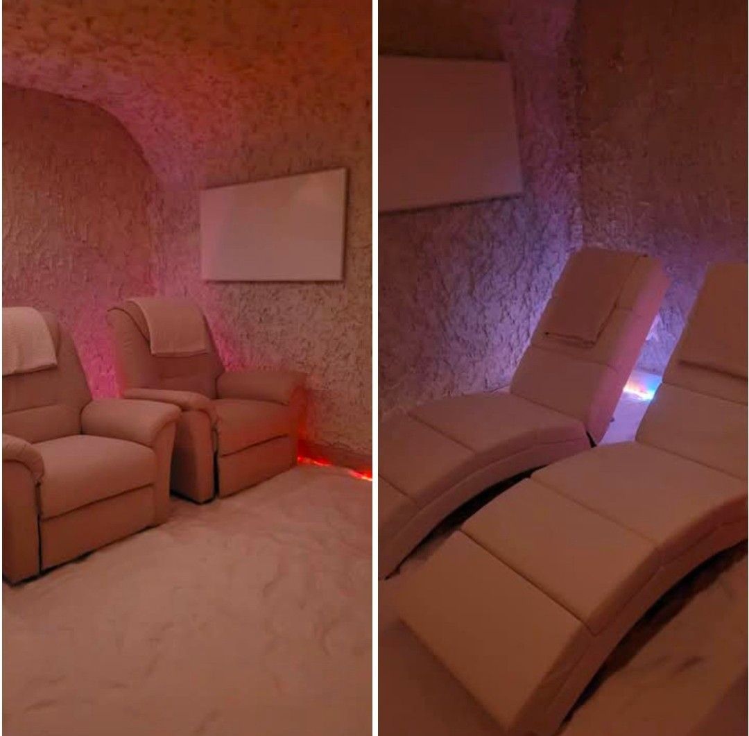 Ein gemütlicher Innenbereich zur Entspannung mit zwei Liegestühlen, einer mit einem Handtuch darauf, beleuchtet von rosa Lichtern.