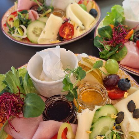 Drei Teller mit verschiedenen Lebensmitteln: Käse, Fleisch, Gemüse, Früchte und eine Schüssel Dip.