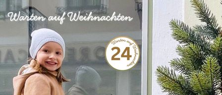 Ein kleines Mädchen in Winterkleidung zeigt auf einen Weihnachtsbaum vor einem Ladenfenster. Sie trägt einen Hut und Stiefel. Der Laden hat ein Weihnachtsverkaufsschild.