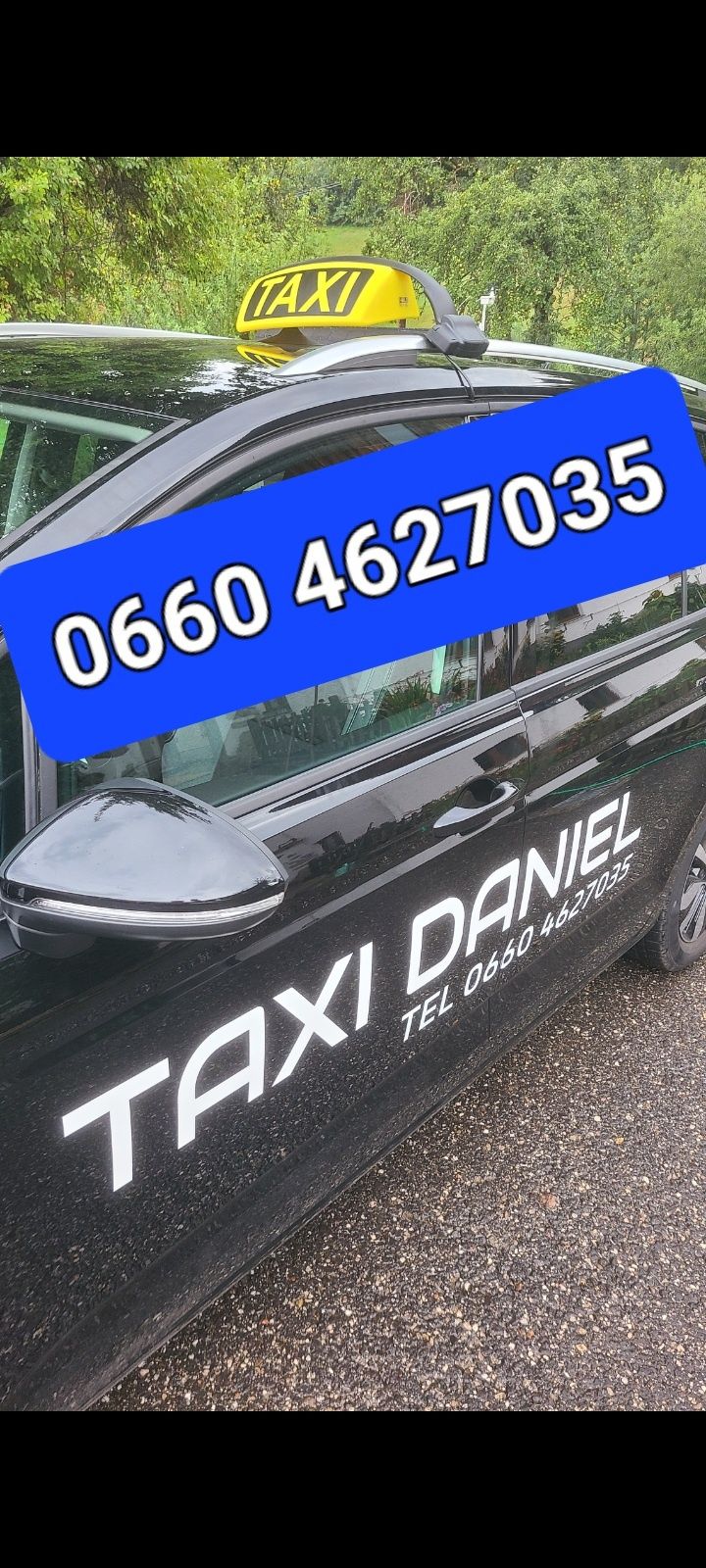 A black taxi car with white text reading 'TAXI DANIEL' and a blue sticker with the number '0660 4627035' on the side door.