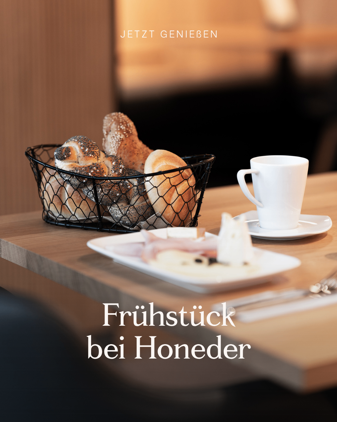 Ein Tisch mit einem Korb voller Brot, einer Tasse, einer Untertasse und einem Teller mit Fleisch, Käse und Gemüse. Die Bildunterschrift lautet 'Frühstück bei Honeder'.