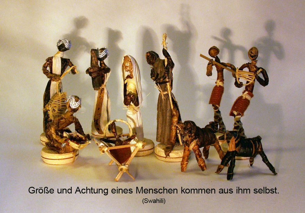 Eine Sammlung von Holzfiguren, die verschiedene Figuren darstellen, einschließlich eines Mannes mit einem Stab, einer Frau mit einem Baby und einem Mann, der ein Musikinstrument spielt. Die Figuren sind auf einer weißen Oberfläche platziert.