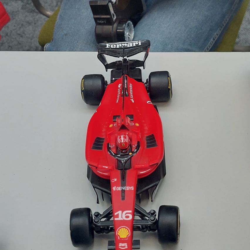 Ein rotes Ferrari F1-Automodell wird auf einem weißen Tisch ausgestellt und zeigt sein schlankes Design und Sponsorenlogos.