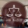 Logo für Gasthof zum Richter mit einer Waage der Gerechtigkeit und einem braunen Hintergrund mit Restaurant-Einrichtung.