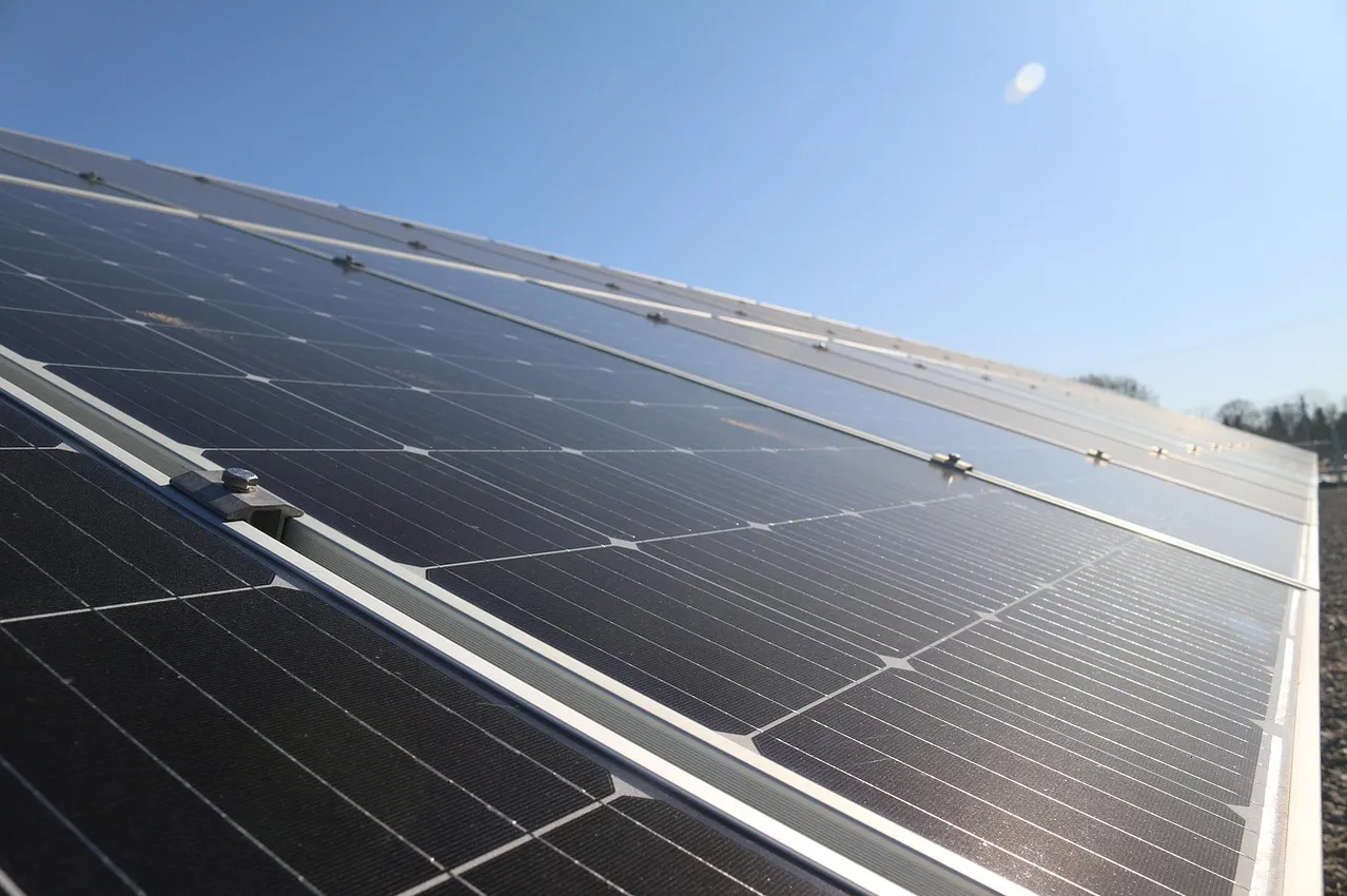 Nahaufnahme mehrerer Solarmodule, die auf einem Dach gegen einen klaren blauen Himmel installiert sind.