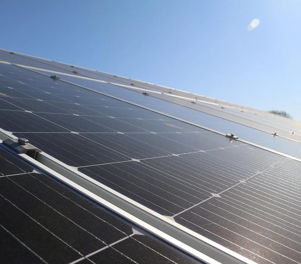 Nahaufnahme mehrerer Solarmodule, die auf einem Dach gegen einen klaren blauen Himmel installiert sind.