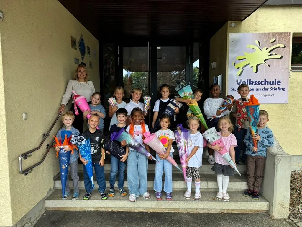 Eine Gruppe von Kindern, einige mit bunten Blumensträußen, posiert für ein Foto vor einem Gebäude.