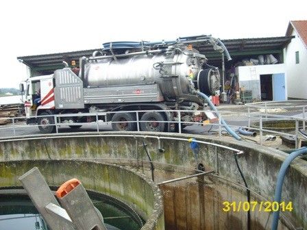 Ein großer weißer Lkw mit einem silbernen Tank steht neben einem Betontank. Der Lkw hat einen großen Schlauch, der mit dem Tank verbunden ist. Ein Datumsstempel vom 31/07/2014 befindet sich auf dem Bild.